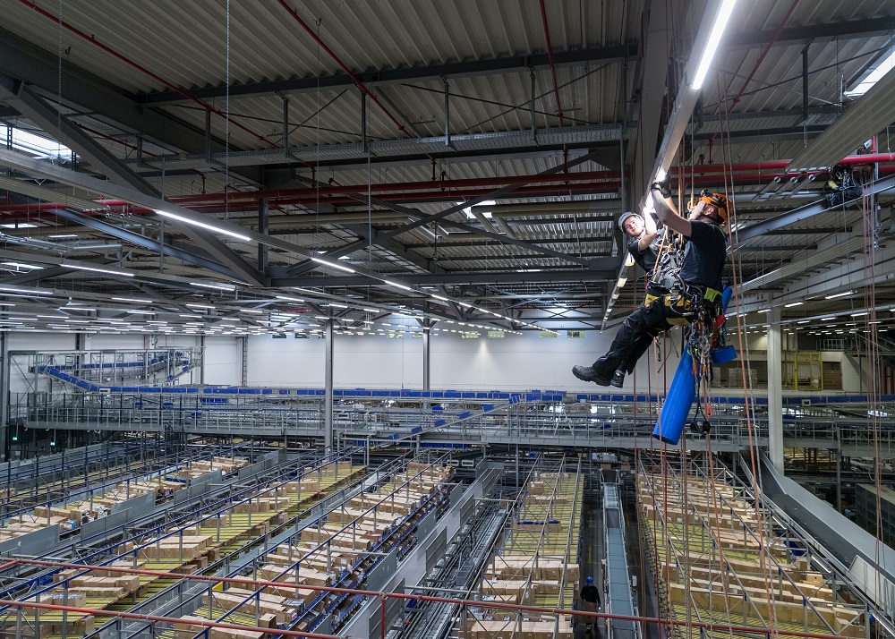 In the Tchibo high-bay warehouse in Bremen, two BLG employees replace one of around 250 fluorescent tubes with LED lamps.
